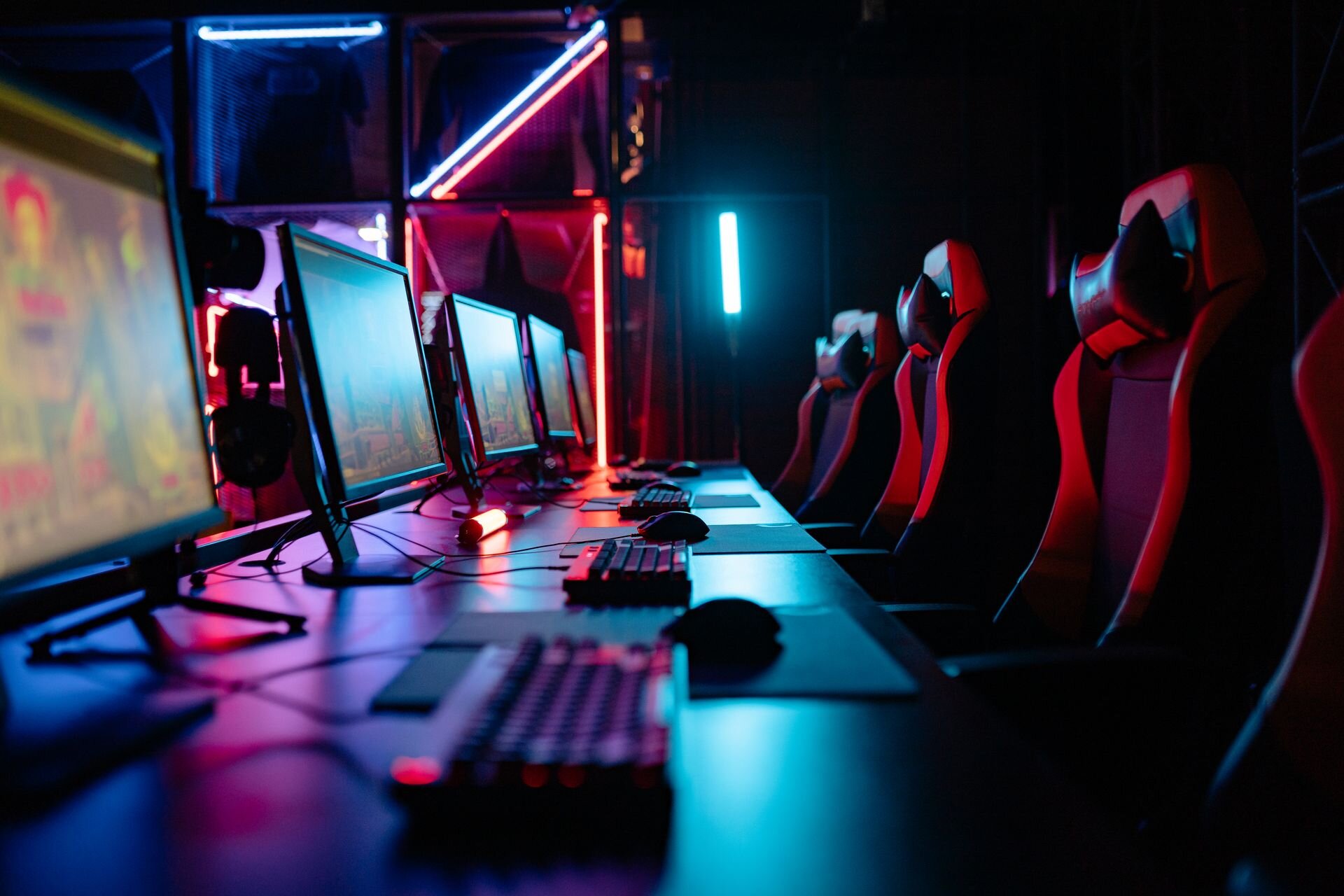 Rows of gaming stations and chairs in a neon-lit esports arena