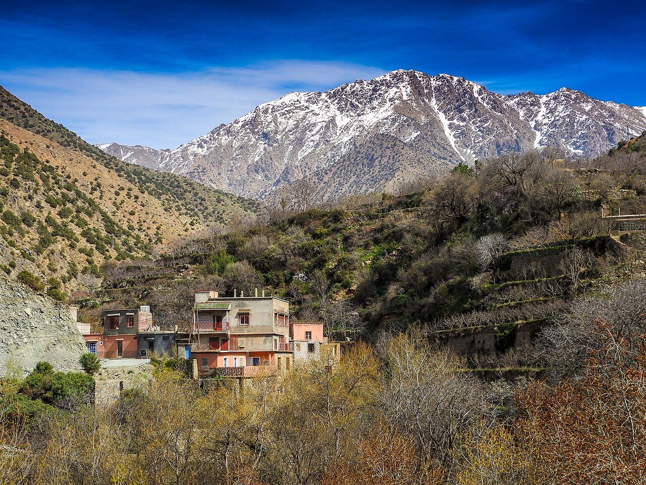 A hillside village in the Ourika Valley below a snow-capped peak of the High Atlas, Morocco.