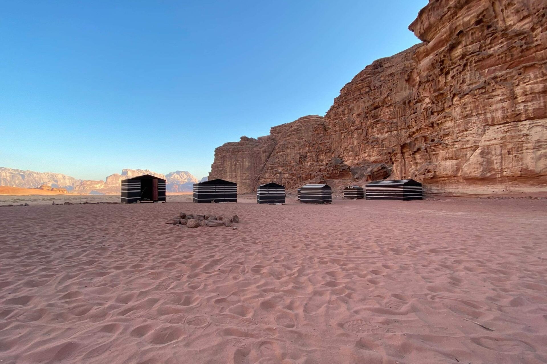 Striped Bedouin tents below a sandstone cliff in Wadi Rum, Jordan
