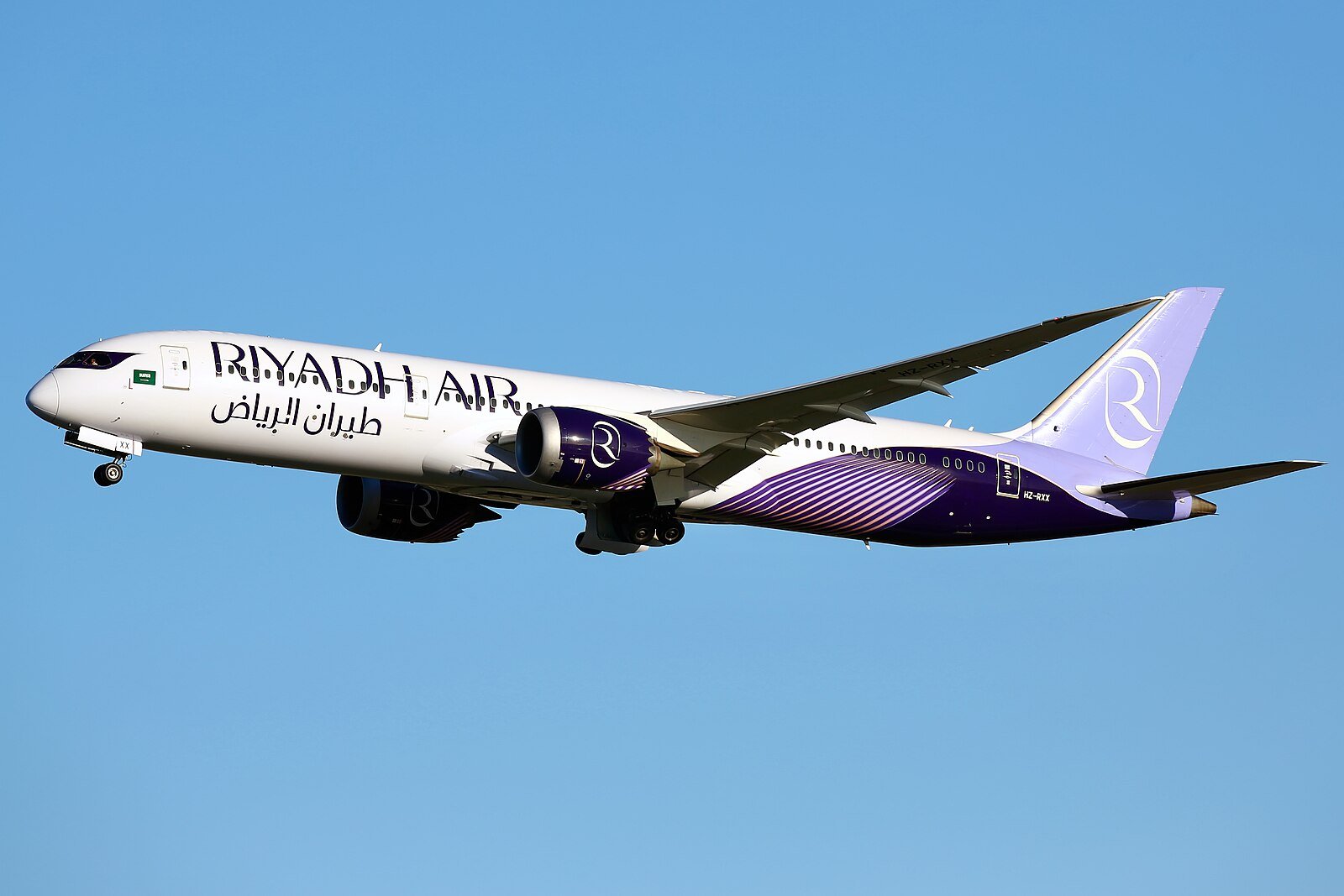 A Riyadh Air Boeing 787-9 Dreamliner in its lavender and white livery climbing into a clear blue sky.