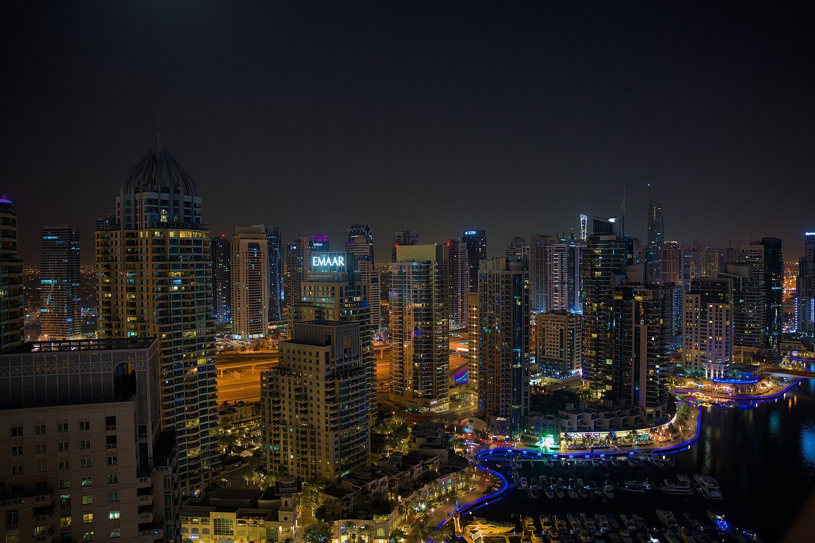 The towers of Dubai Marina glitter at night above the lit curve of the marina's waterfront promenade.