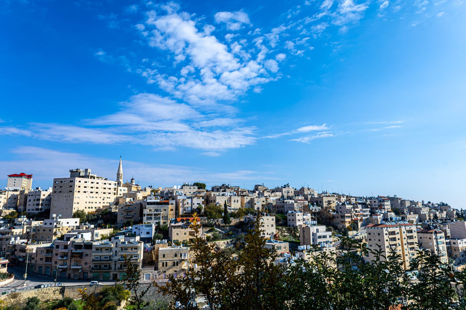 Bethlehem's stone houses and church spire under a bright blue sky