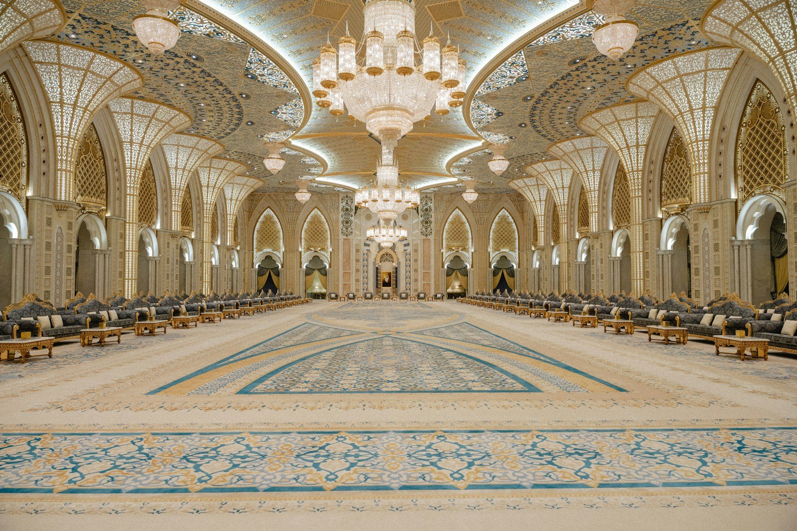 A crystal chandelier above the patterned carpets and carved golden arches of a grand hall inside Qasr Al Watan, Abu Dhabi.