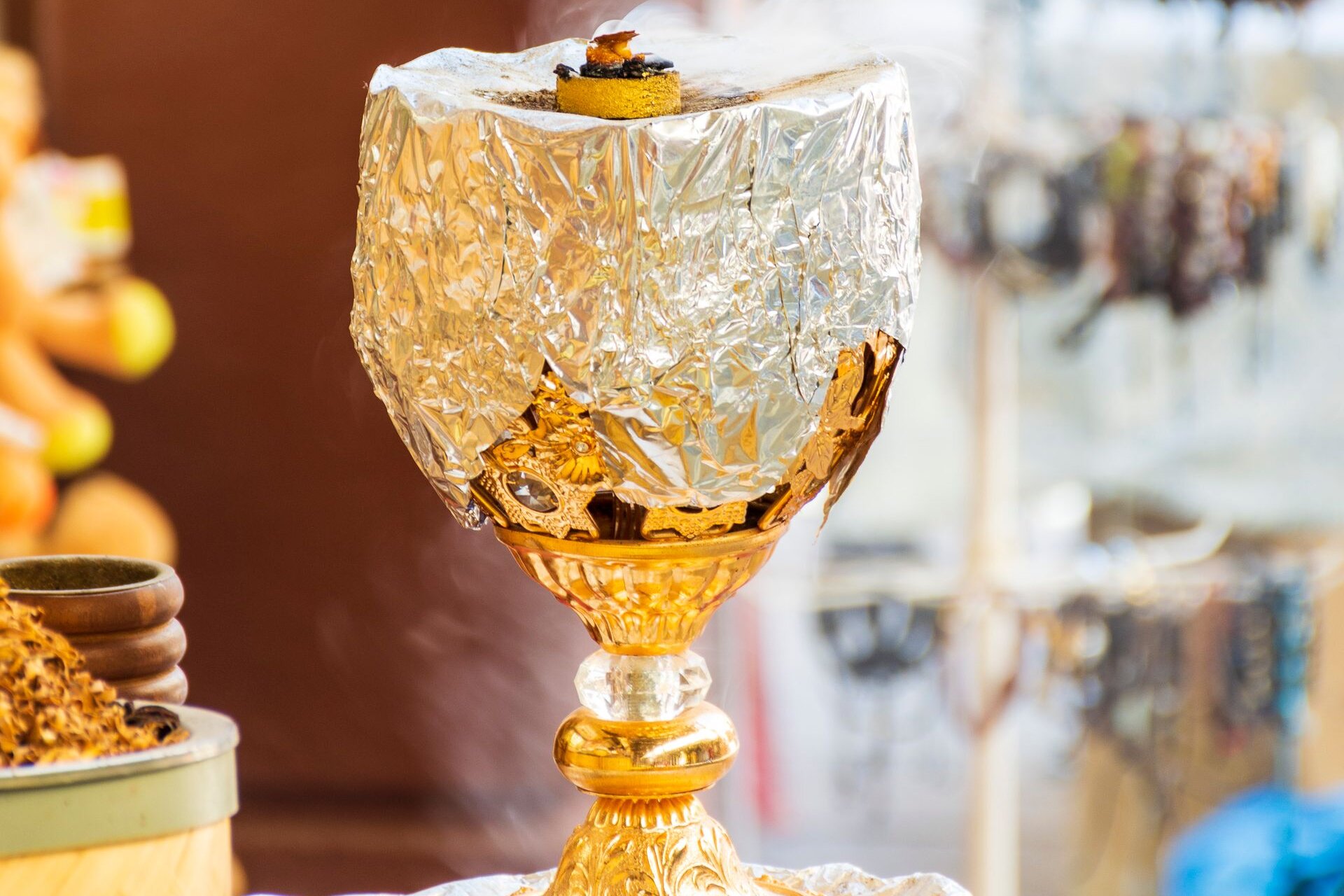 A gilded incense burner with smoking bakhoor and oud in a souk