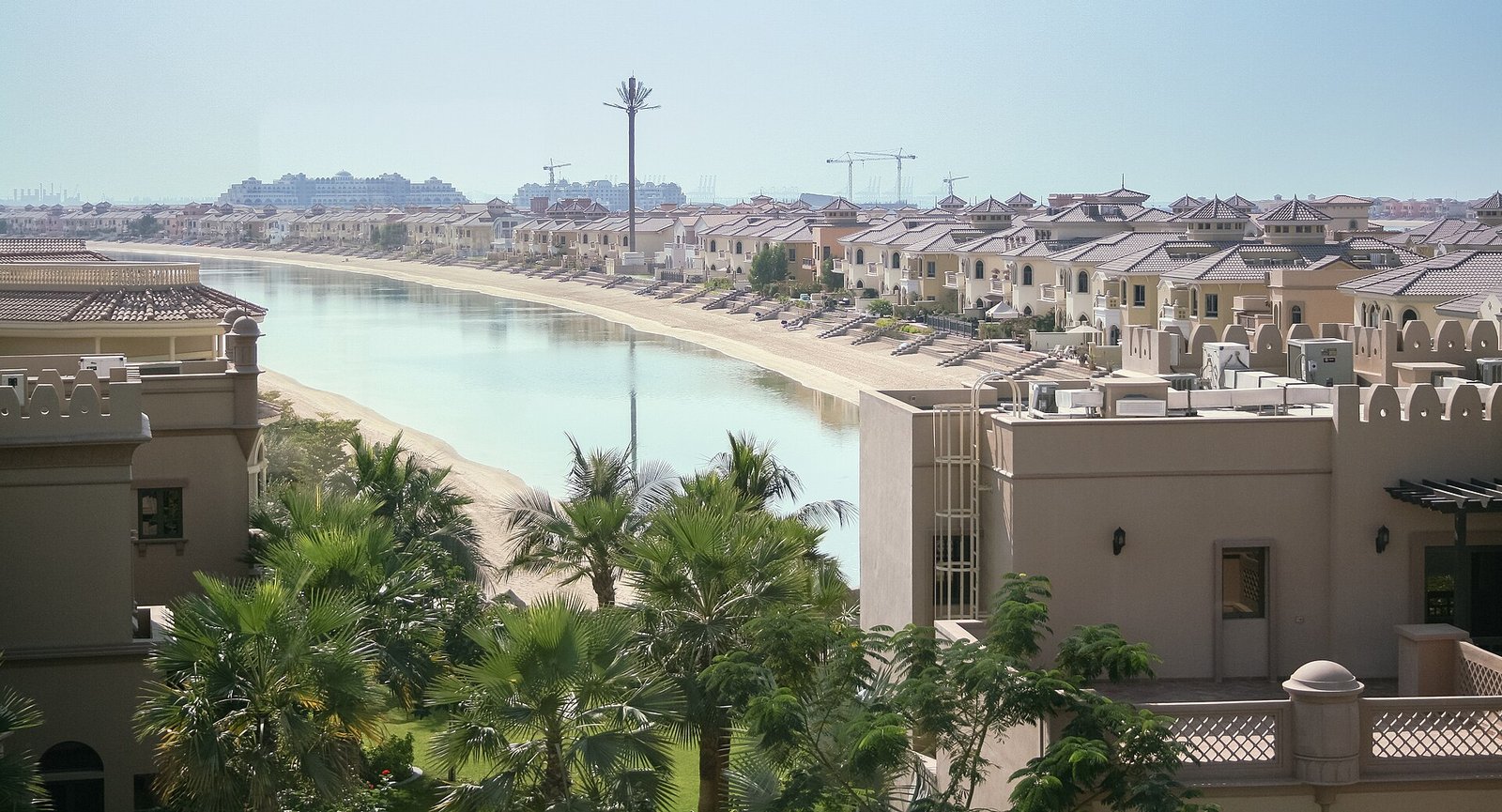 Palm gardens and a long pool winding between the sand-colored villas of Qasr Al Sarab resort in the Liwa desert, Abu Dhabi.