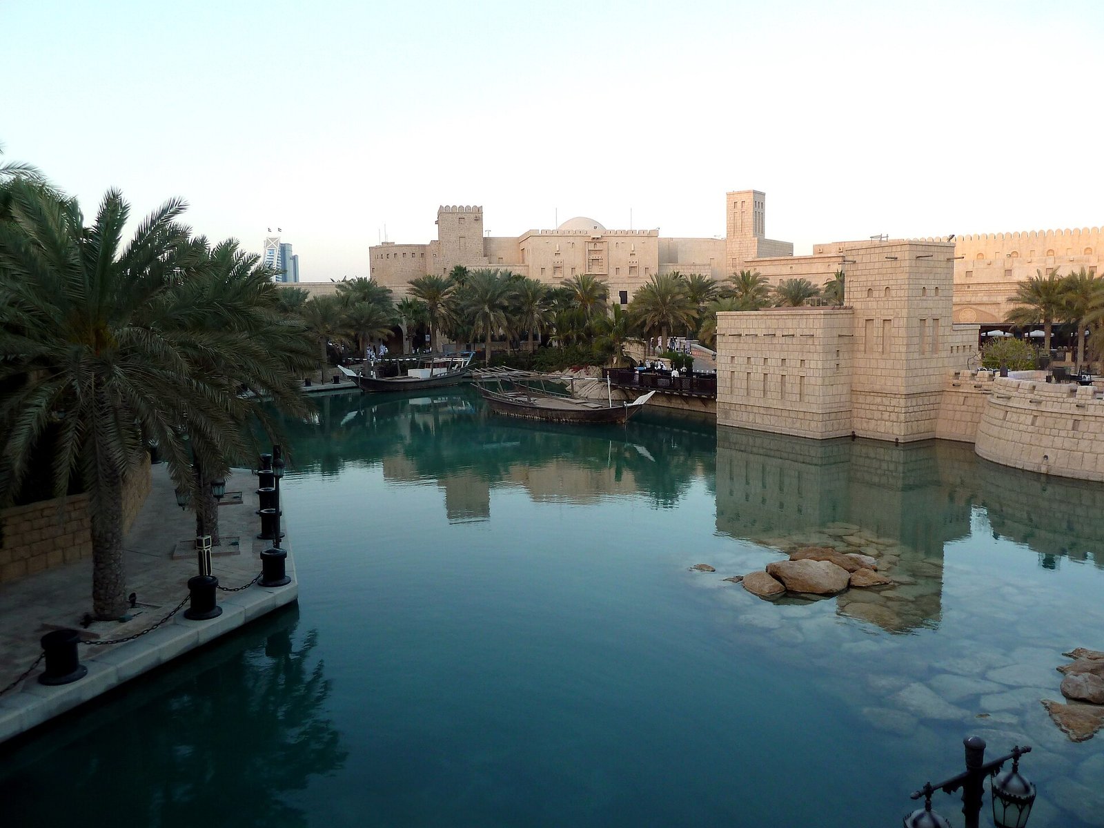 The turquoise waterways and sand-colored towers of Souk Madinat Jumeirah, Dubai, framed by palms