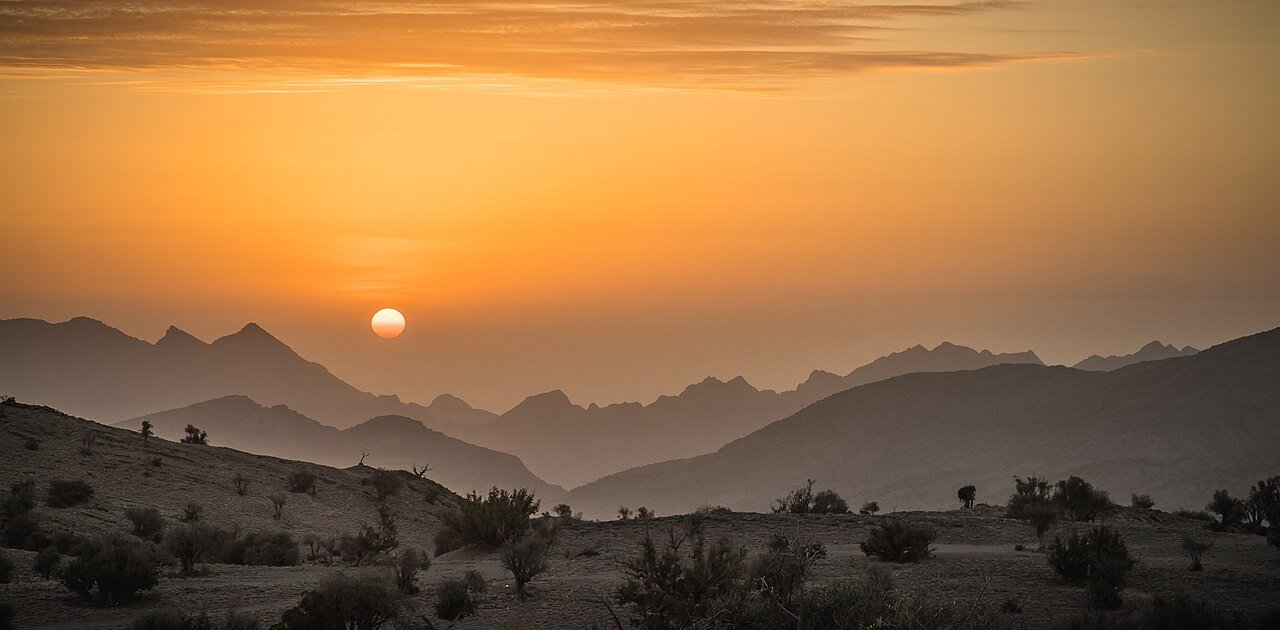 The sun rising over layered mountain ridges on Jebel Akhdar, Oman's Green Mountain.