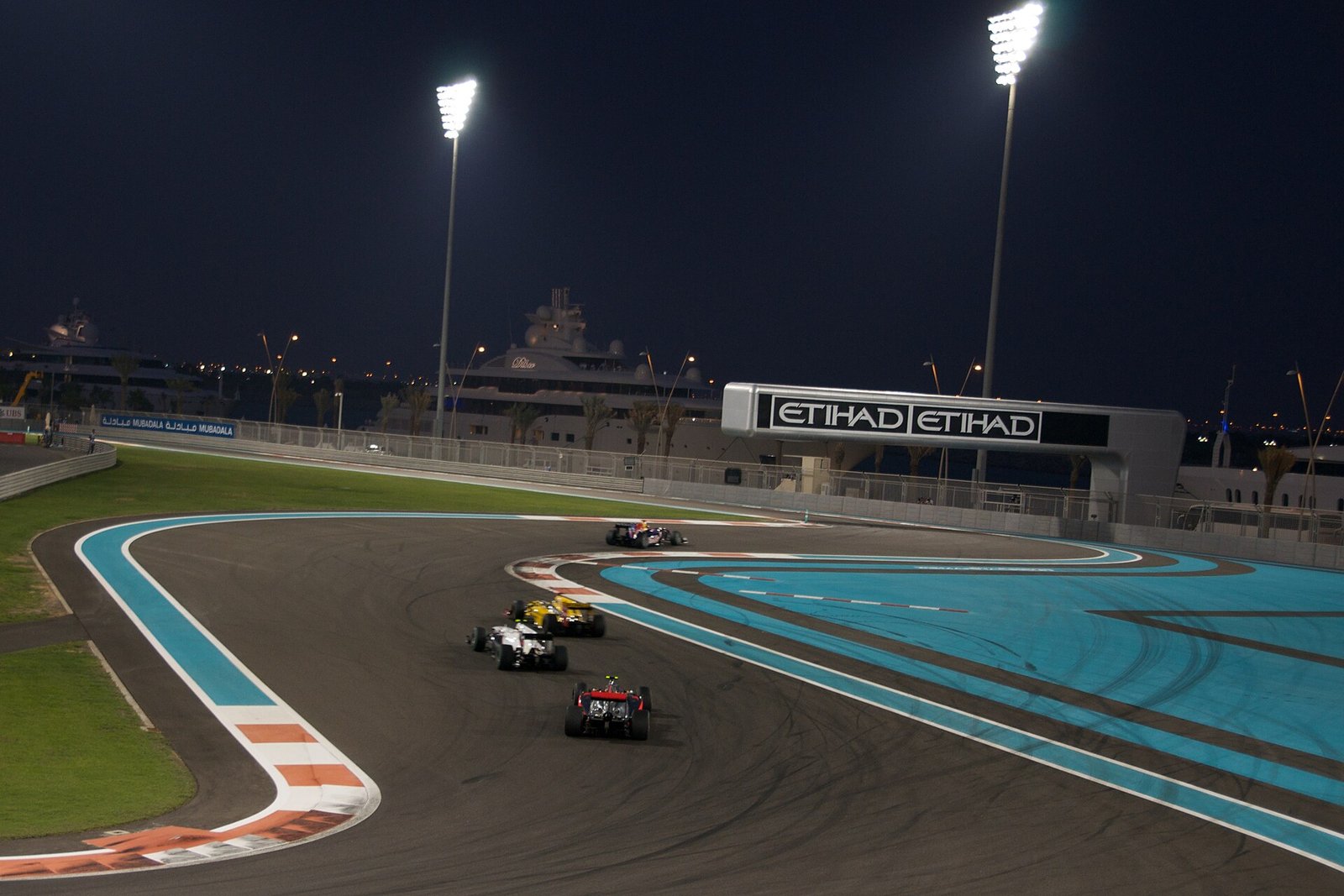 Formula One cars racing under the floodlights of the Yas Marina Circuit at night, Abu Dhabi.