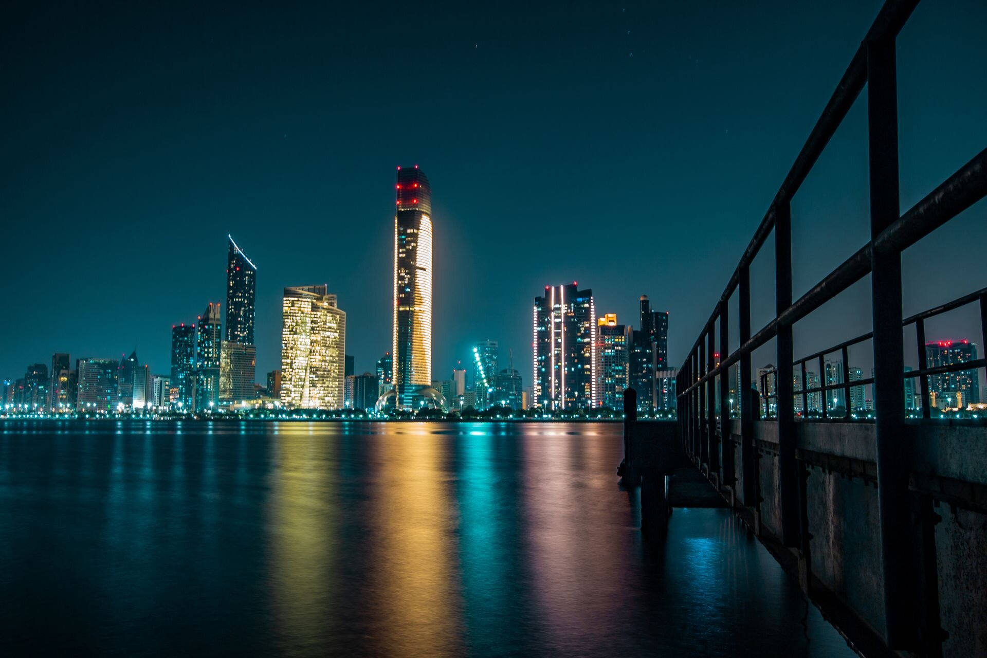 The Abu Dhabi skyline lit up at night, reflected in the water